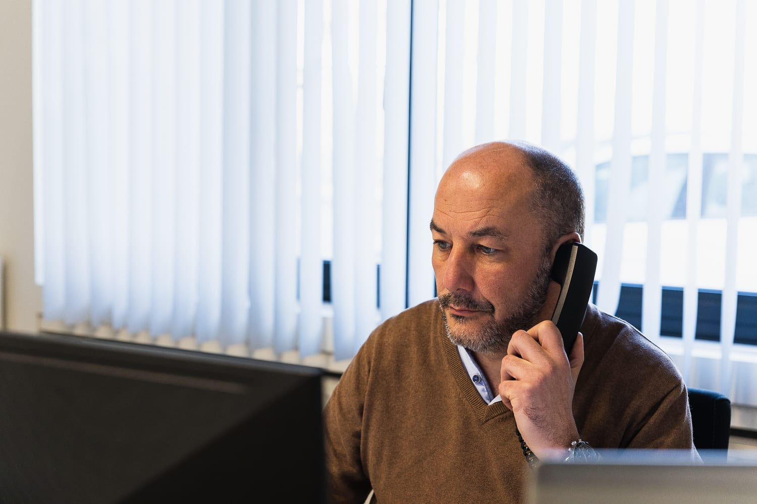 Een mannelijke Climatrix-collega zit achter zijn computer te telefoneren.