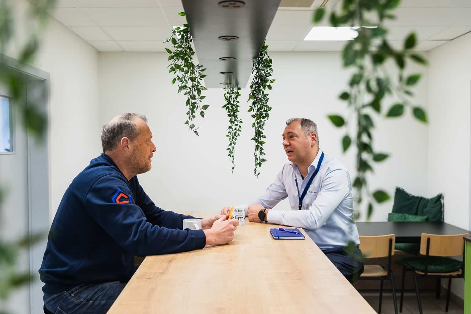 2 medewerkers van Climatrix, ook wel Climaten genoemd, zitten aan tafel om de lopende zaken te bespreken.